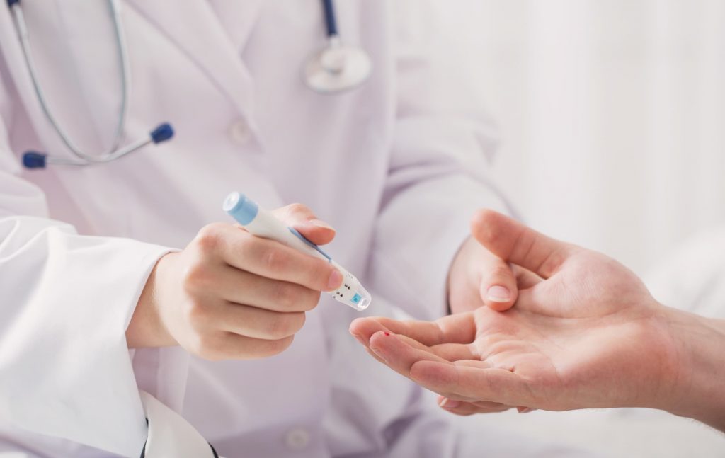 white nurse taking blood sugar of white patient to check blood glucose levels