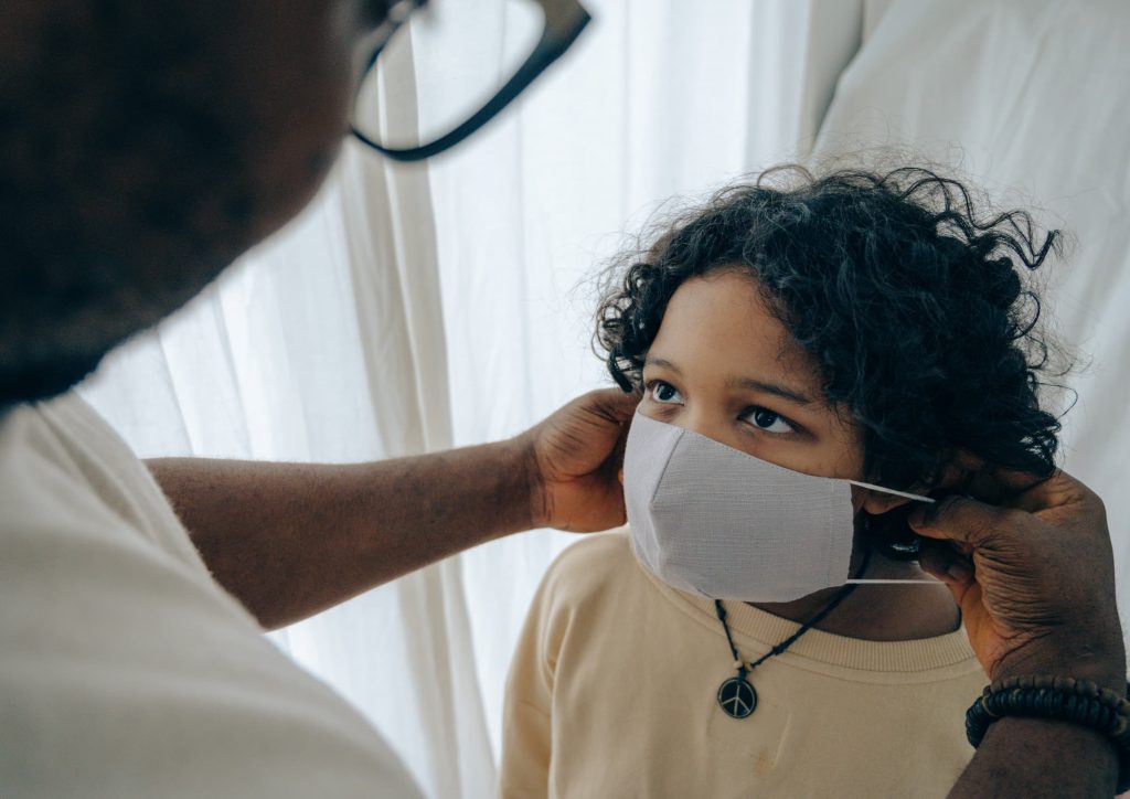 dad putting mask on son's face everyone wear a mask during super bowl party