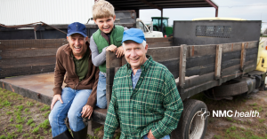 multigenerational family of farmers sitting on the back of a truck smiling