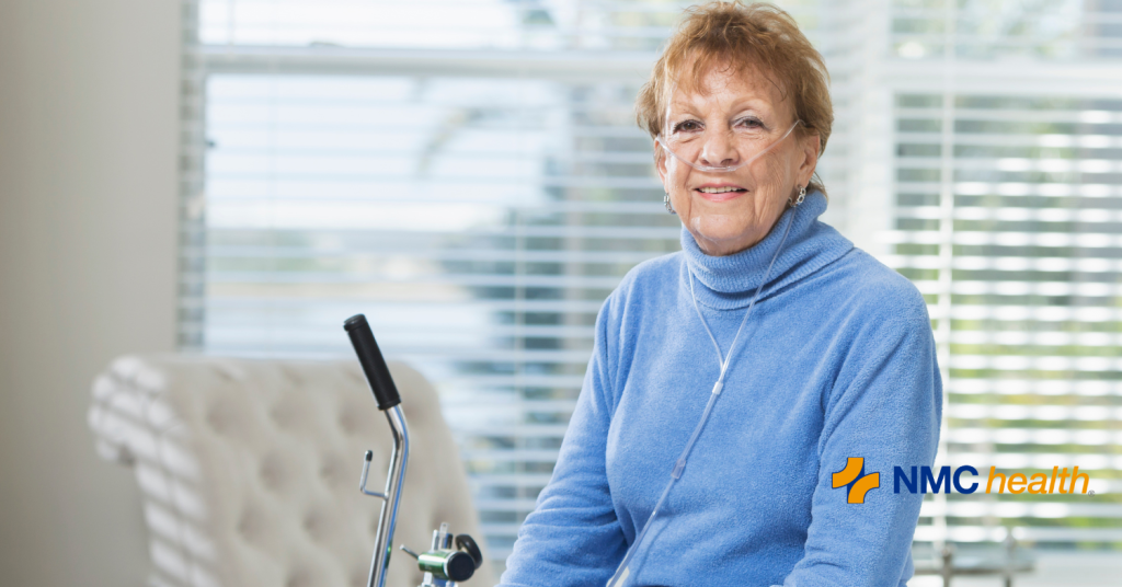 elderly woman sitting and smiling with oxygen tank next to her