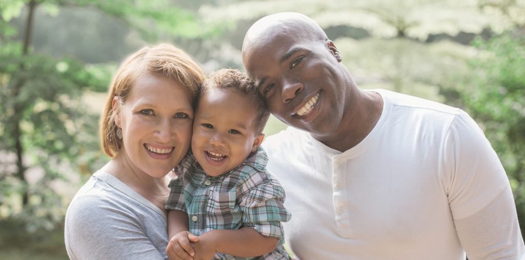 man woman and toddler smiling and looking at camera