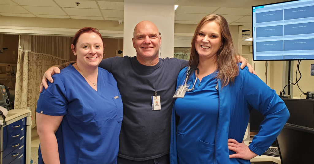 two female nurses and one male nurse smiling and looking at the camera