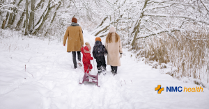 young family walking in snow with sled