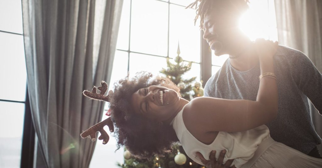 african american woman and man dancing in front of christmas tree