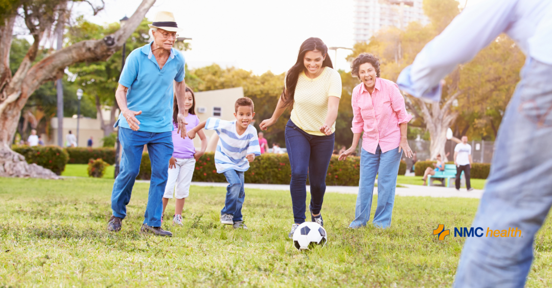 happy family of all ages playing soccer on green grass